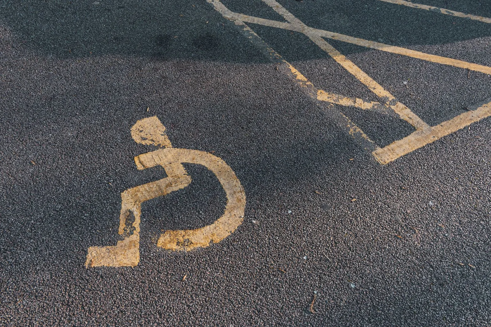 A faded disabled parking symbol painted on asphalt pavement, highlighting accessibility.